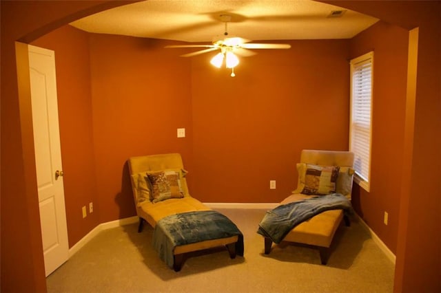 living area featuring a wealth of natural light, carpet floors, and ceiling fan