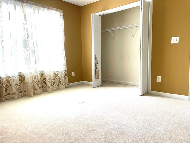 unfurnished bedroom with light carpet and a closet