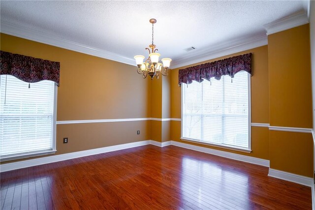 unfurnished room featuring wood-type flooring, ornamental molding, a textured ceiling, and an inviting chandelier