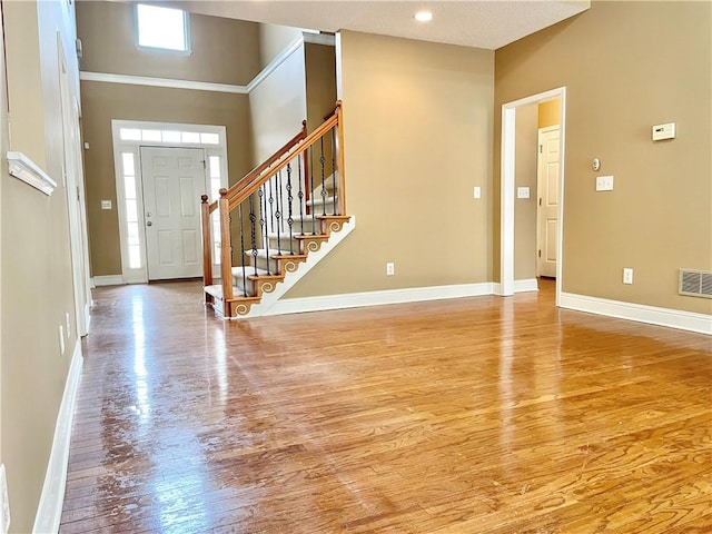 foyer entrance featuring a towering ceiling and light wood-type flooring