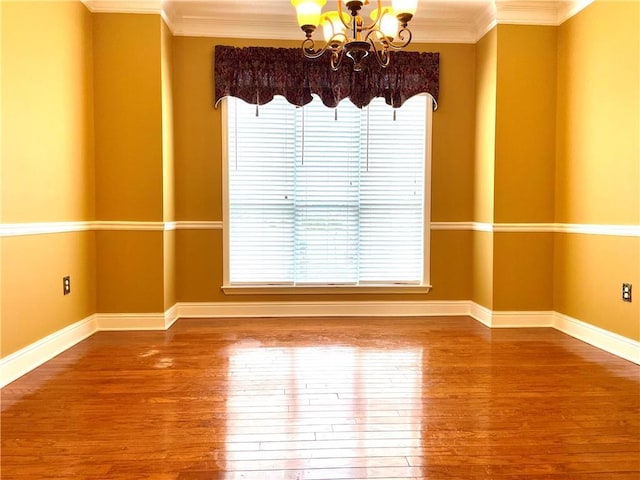 spare room with crown molding, a healthy amount of sunlight, hardwood / wood-style floors, and a notable chandelier