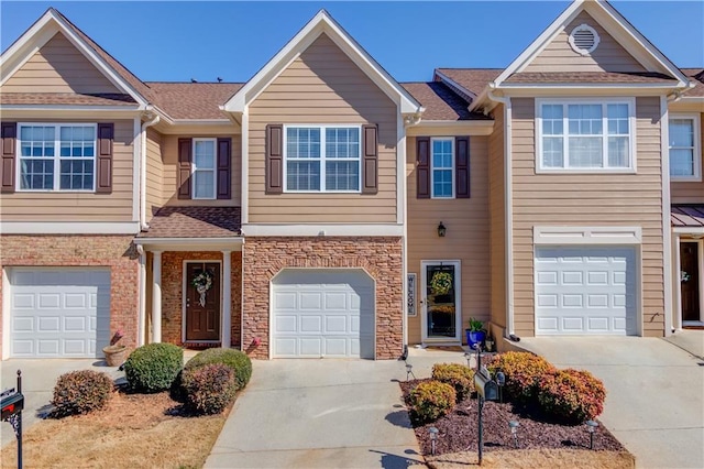 multi unit property featuring a garage, stone siding, concrete driveway, and a shingled roof