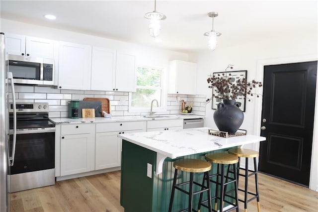 kitchen with a kitchen island, white cabinetry, pendant lighting, and stainless steel appliances