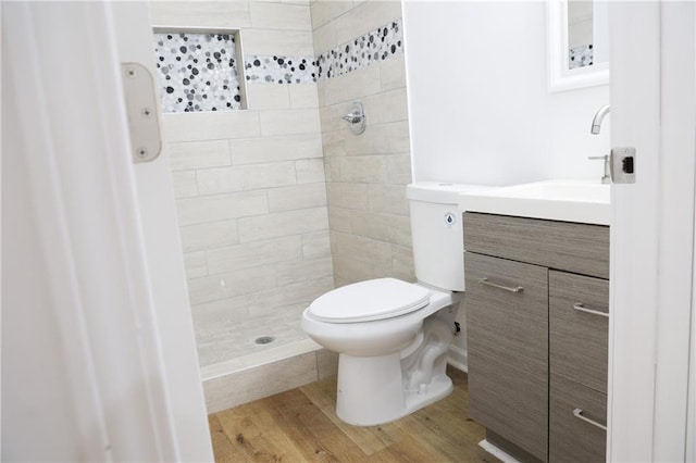 bathroom with vanity, hardwood / wood-style floors, tiled shower, and toilet