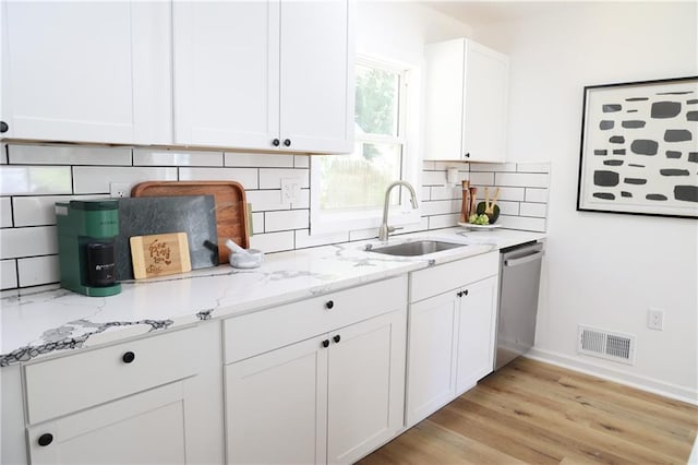 kitchen featuring tasteful backsplash, sink, white cabinetry, light hardwood / wood-style floors, and stainless steel dishwasher