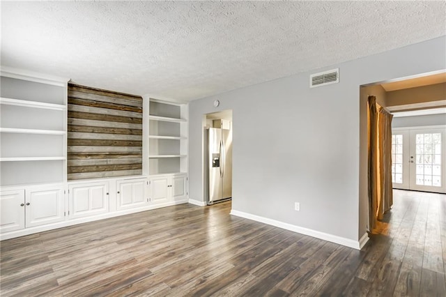 unfurnished living room with french doors, a textured ceiling, built in shelves, and dark hardwood / wood-style flooring