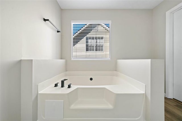 bathroom with wood finished floors and a bath