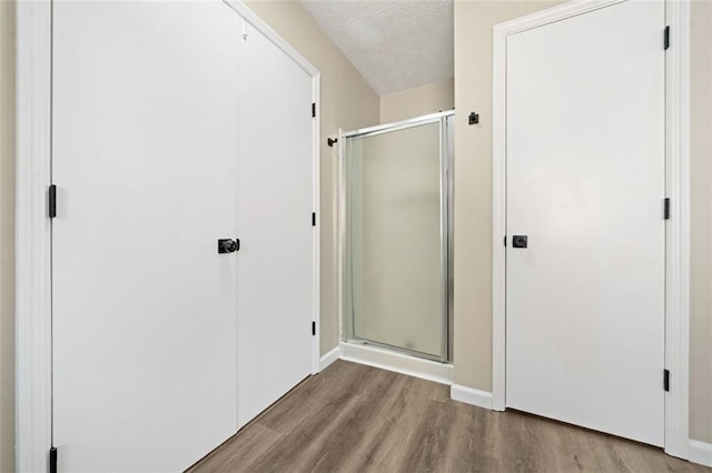 bathroom featuring a stall shower, a textured ceiling, and wood finished floors