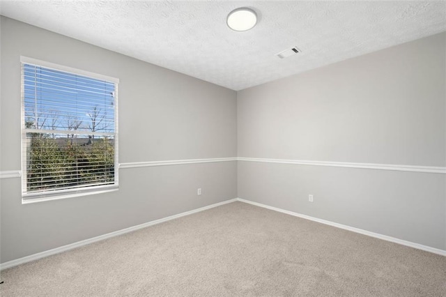 carpeted empty room with visible vents, a textured ceiling, and baseboards