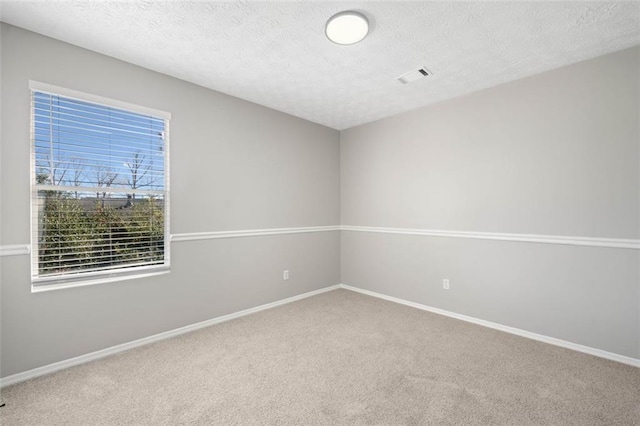 carpeted empty room with baseboards and a textured ceiling