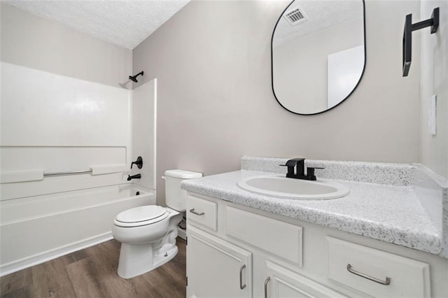 full bathroom featuring vanity, toilet, wood finished floors, and a textured ceiling