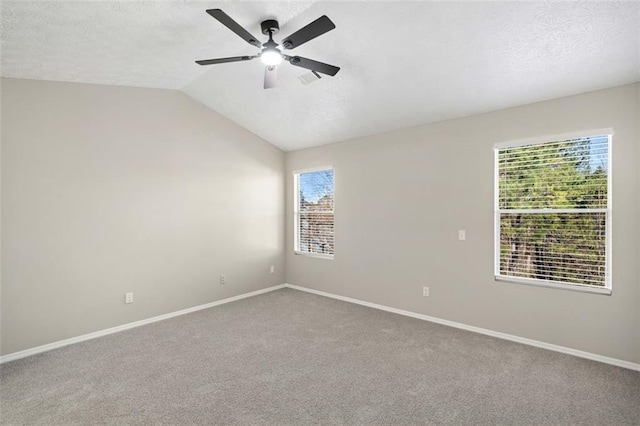empty room featuring a ceiling fan, baseboards, carpet, a textured ceiling, and vaulted ceiling