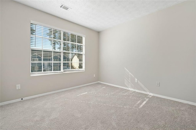 carpeted spare room featuring visible vents, a textured ceiling, and baseboards