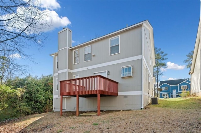 rear view of house featuring a deck, a chimney, and central AC