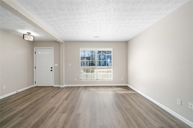 interior space featuring a textured ceiling, baseboards, and wood finished floors