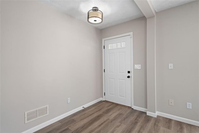foyer with wood finished floors, a textured ceiling, and baseboards