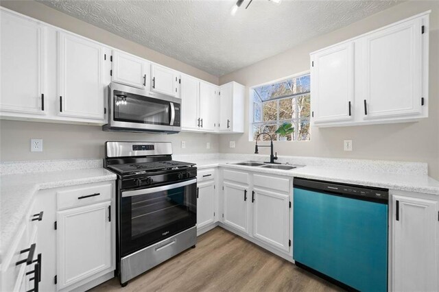 kitchen featuring a sink, light wood-style flooring, white cabinetry, and stainless steel appliances