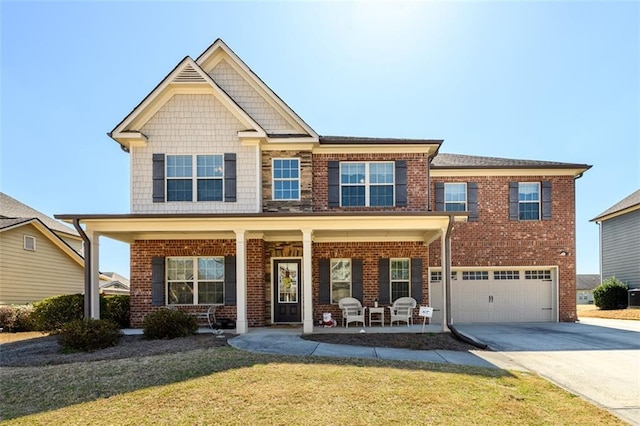 craftsman house featuring brick siding, a porch, a front yard, a garage, and driveway