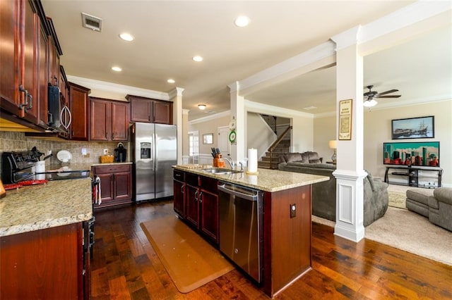 kitchen featuring a sink, open floor plan, ornate columns, and stainless steel appliances