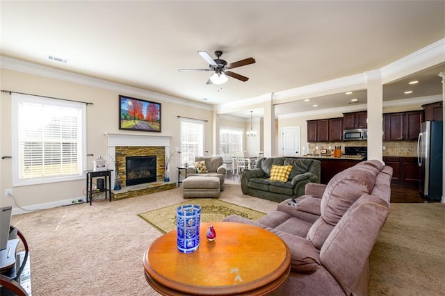 living area featuring baseboards, a fireplace, ceiling fan, ornamental molding, and carpet flooring