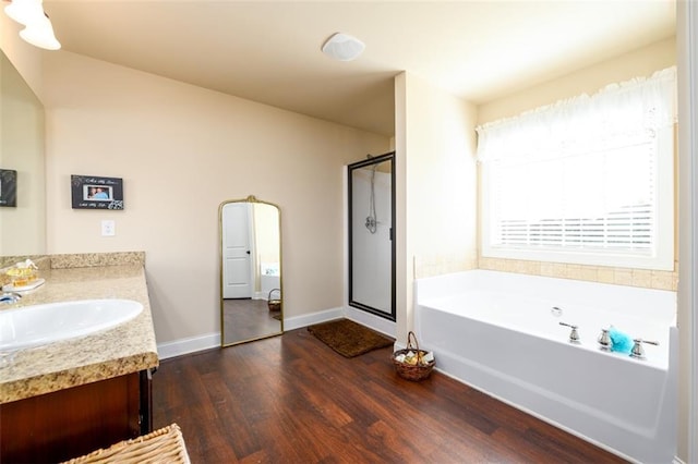 bathroom with a shower stall, baseboards, a garden tub, wood finished floors, and vanity