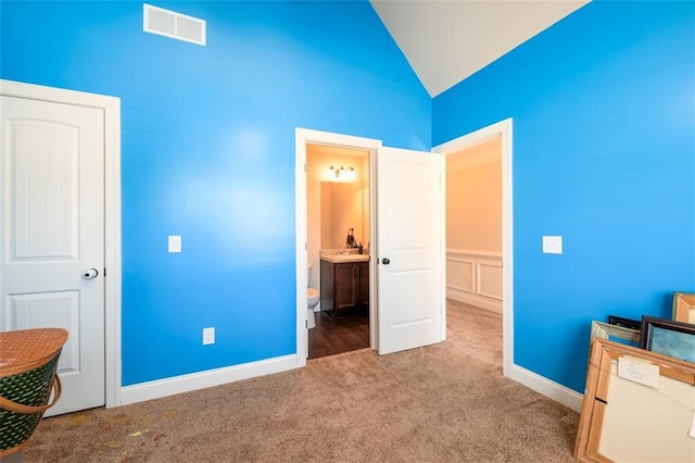 bedroom with carpet, visible vents, baseboards, lofted ceiling, and ensuite bathroom