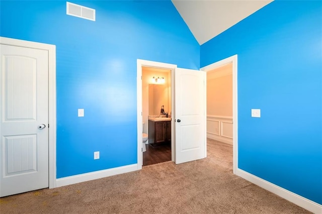 unfurnished bedroom with visible vents, baseboards, vaulted ceiling, carpet flooring, and ensuite bathroom