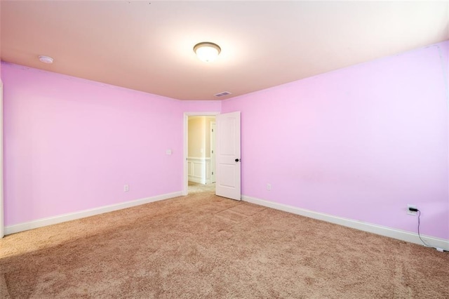 empty room featuring visible vents, light colored carpet, and baseboards