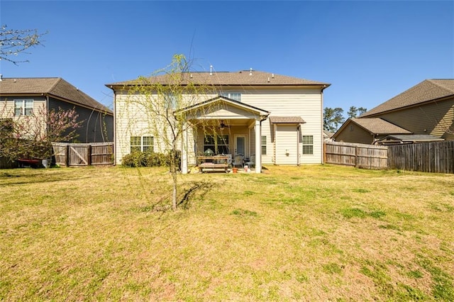 rear view of house featuring a yard and a fenced backyard