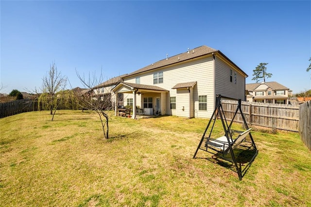 rear view of house with a patio area, a yard, and a fenced backyard