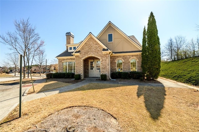 view of front of house featuring french doors, brick siding, and a chimney