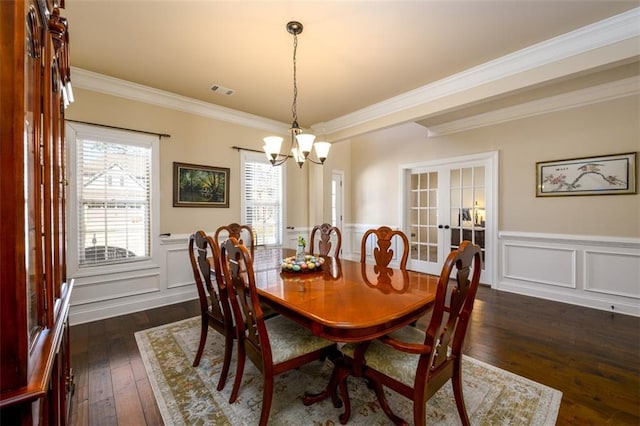 dining space featuring dark wood-style floors, french doors, a wainscoted wall, and ornamental molding