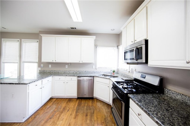 kitchen with a wealth of natural light, light wood-type flooring, white cabinetry, and stainless steel appliances