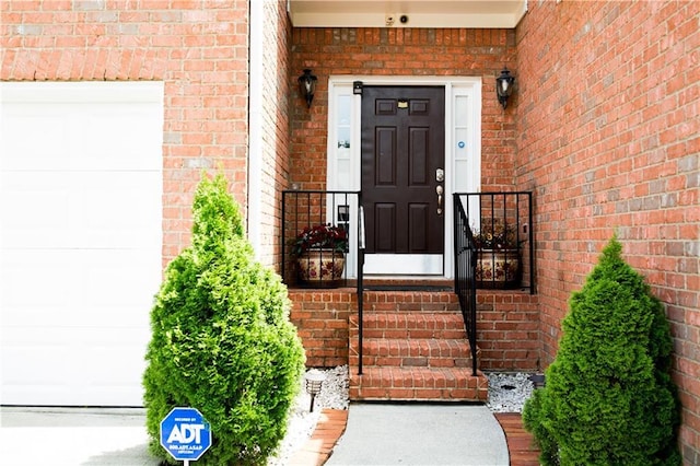 property entrance with a garage and brick siding