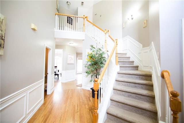 staircase featuring hardwood / wood-style floors and a towering ceiling