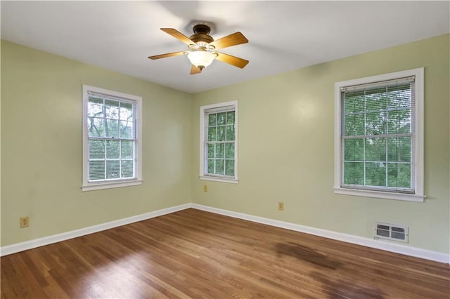 unfurnished room with wood finished floors, baseboards, a ceiling fan, and visible vents