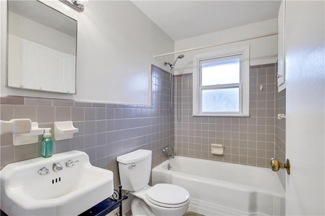 full bathroom featuring bathing tub / shower combination, toilet, a sink, wainscoting, and tile walls
