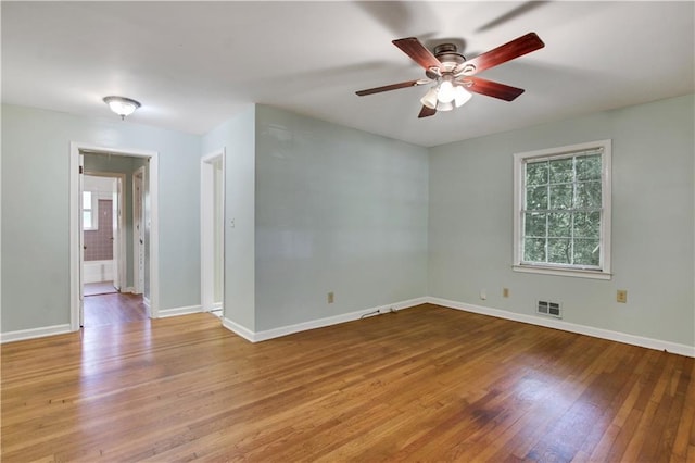 empty room with baseboards, a ceiling fan, visible vents, and hardwood / wood-style flooring