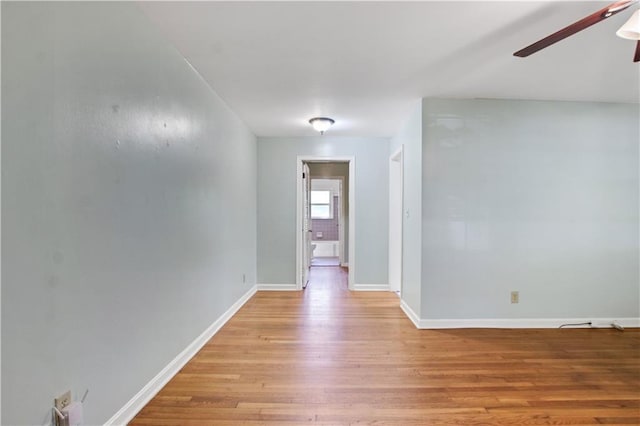 empty room featuring light wood finished floors, ceiling fan, and baseboards