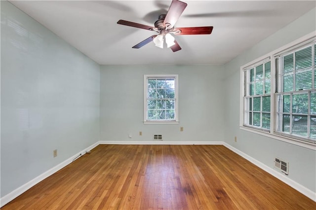 empty room featuring visible vents, baseboards, hardwood / wood-style floors, and ceiling fan