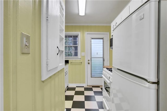 doorway with crown molding, wood walls, baseboards, and dark floors