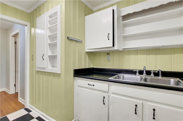 kitchen featuring crown molding, open shelves, a sink, dark countertops, and baseboards