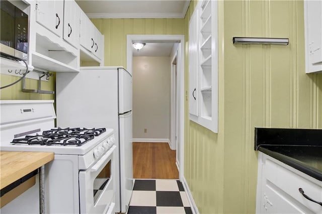 kitchen with white cabinets, baseboards, white gas stove, stainless steel microwave, and tile patterned floors