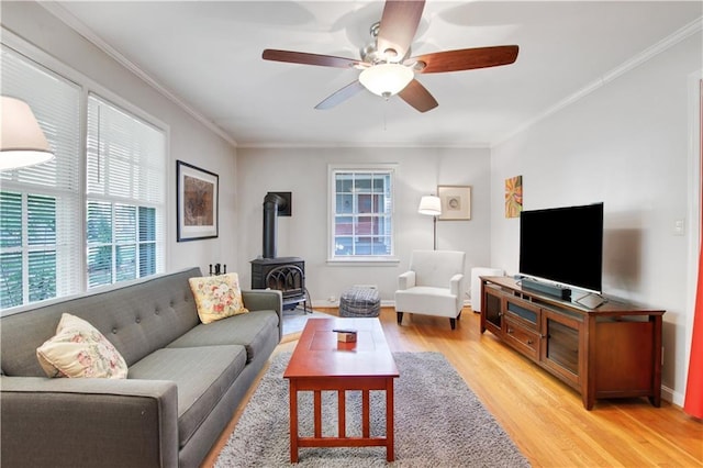 living room with a wood stove, plenty of natural light, light wood-type flooring, and ornamental molding