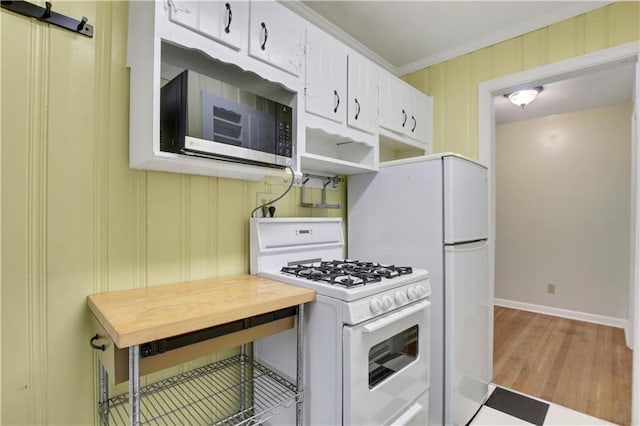 kitchen featuring white gas stove, ornamental molding, white cabinetry, stainless steel microwave, and baseboards