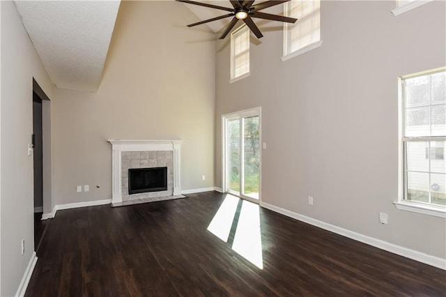 unfurnished living room with dark hardwood / wood-style flooring, ceiling fan, plenty of natural light, and a textured ceiling