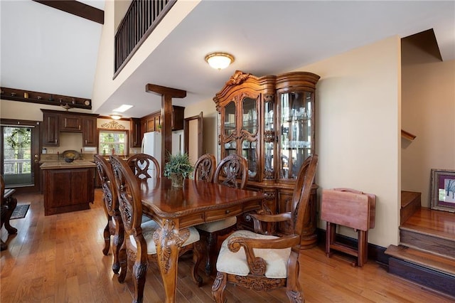 dining space with a high ceiling and light hardwood / wood-style flooring