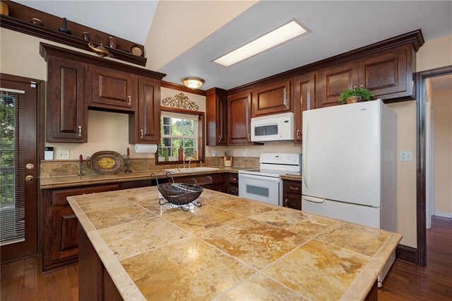 kitchen with dark hardwood / wood-style flooring, a center island, white appliances, and sink