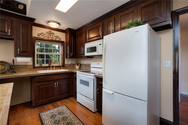 kitchen with dark brown cabinets, white appliances, light hardwood / wood-style flooring, and sink