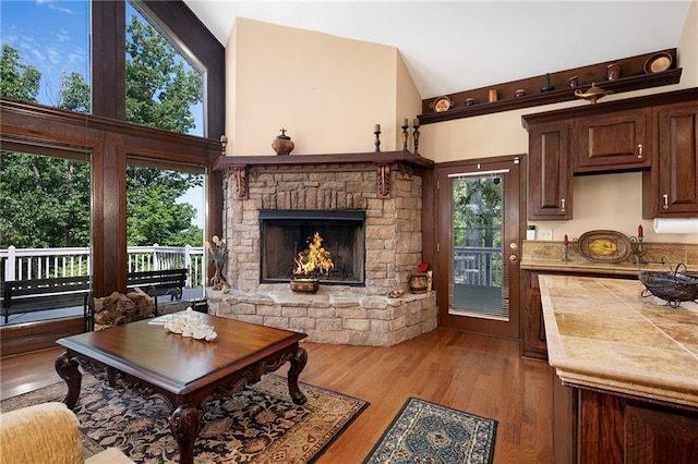 living room featuring a stone fireplace, light hardwood / wood-style flooring, and a towering ceiling